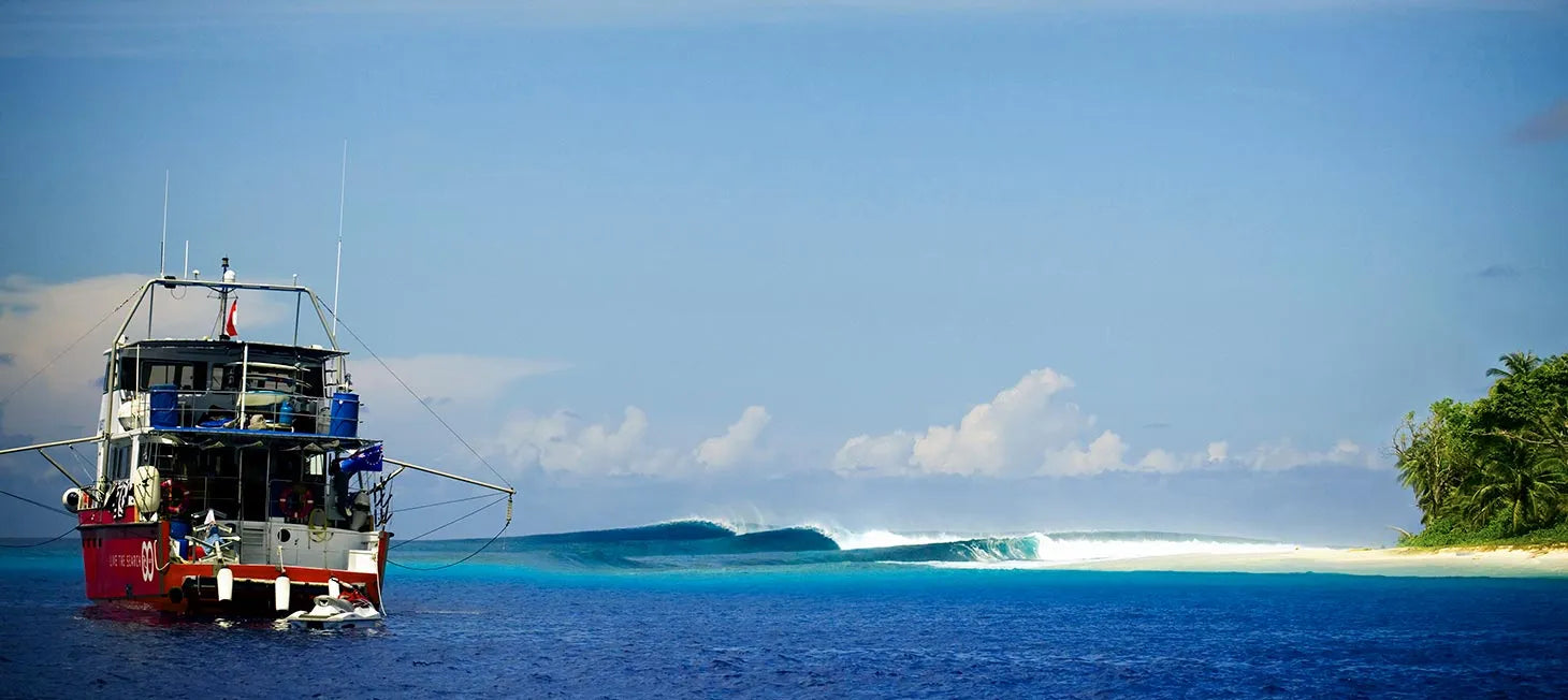 Boat on a clear blue ocean with a distant island and blue sky.