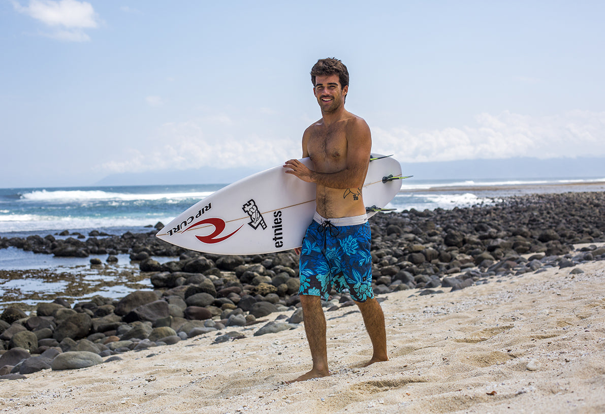 The surfer Mason Ho on the beach with a surfboard