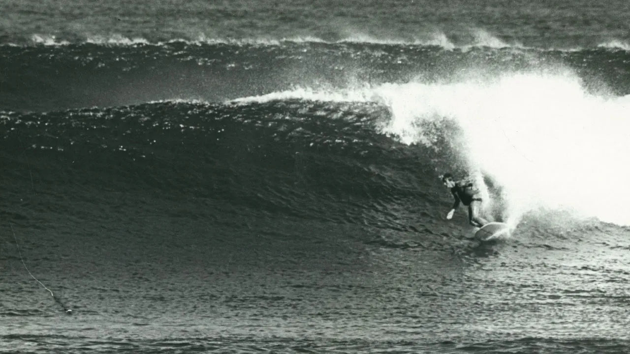 Black and white photo of a surfer riding a wave