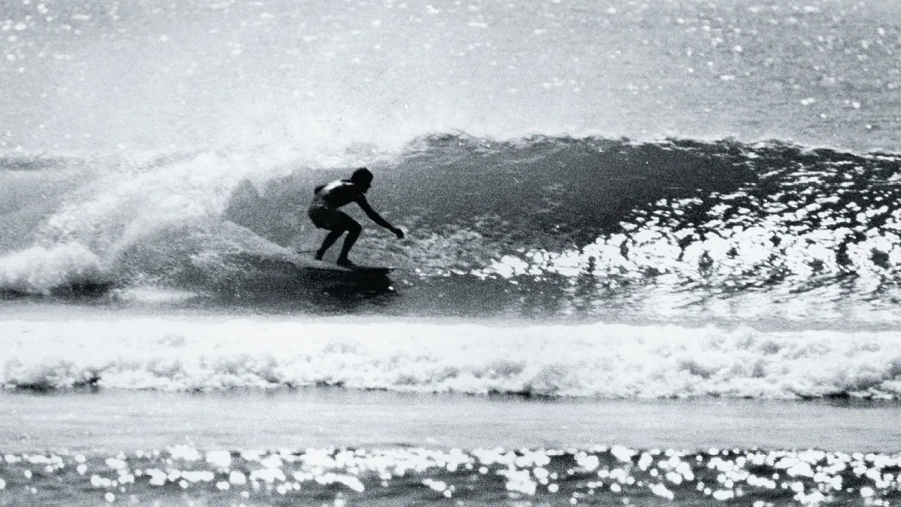 Black and white photo of a surfer riding a wave.