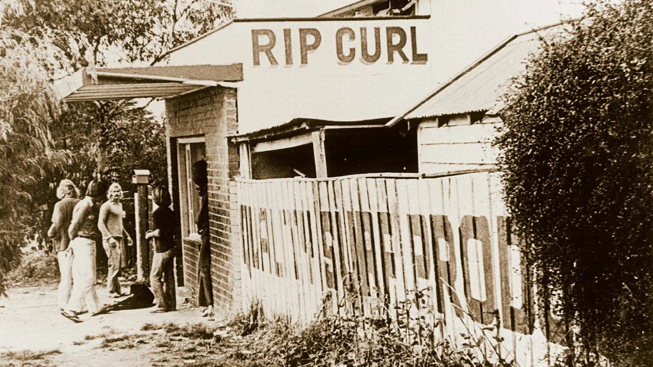 Vintage photo of a building with 'Rip Curl' sign and people around
