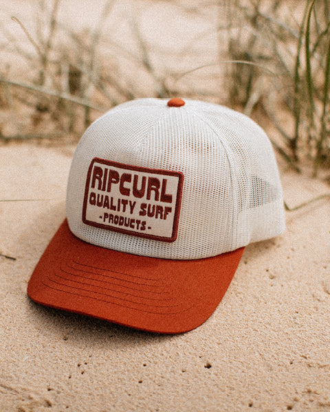 Rip Curl cap with red brim and white mesh back on sand