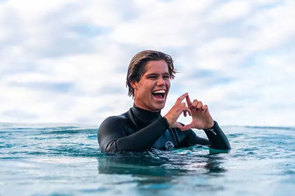 Morgan Cibilic in the water with a blue sky and clouds in the background