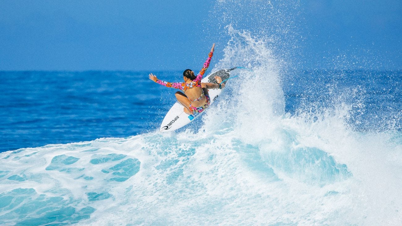 Surfer performing a trick on a wave with a clear blue sky