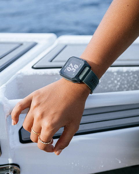 Person wearing a smartwatch with water in the background